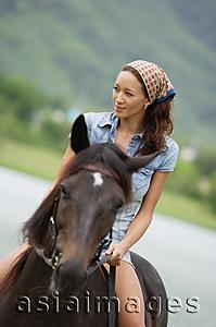 Asia Images Group - Woman sitting on horse, looking away