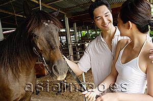Asia Images Group - Couple in stable, standing with horse