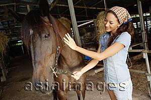 Asia Images Group - Woman petting horse in stable