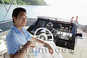 Asia Images Group - Man sitting at helm of yacht, looking at camera