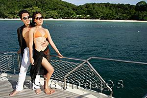 Asia Images Group - Couple standing on boat deck, man with arms around woman