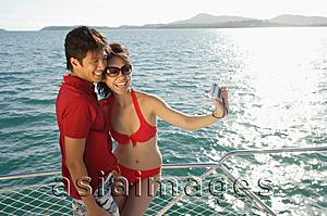 Asia Images Group - Couple on boat deck, taking a picture of themselves
