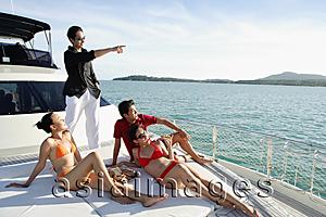 Asia Images Group - Young adults on boat deck, man standing and pointing to the distance