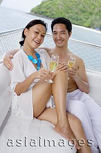 Asia Images Group - Couple sitting on yacht, holding champagne glasses, smiling at camera
