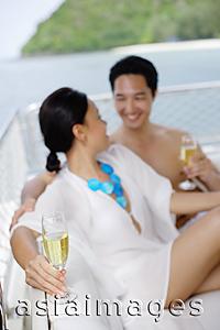 Asia Images Group - Couple sitting on yacht holding champagne glasses