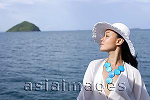 Asia Images Group - Woman wearing white hat, in profile, ocean behind her