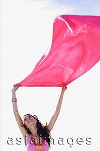 Asia Images Group - Young woman holding piece of cloth in the air, looking up