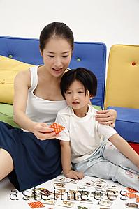 Asia Images Group - Mother and daughter sitting on floor, playing cards