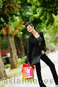 Asia Images Group - Woman dressed in black, holding shopping bags, smiling