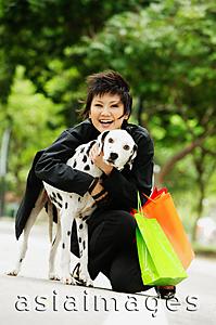 Asia Images Group - Woman with shopping bags embracing Dalmatian