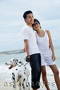 Asia Images Group - Couple standing on beach with Dalmatian