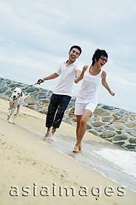Asia Images Group - Couple running on beach with dog