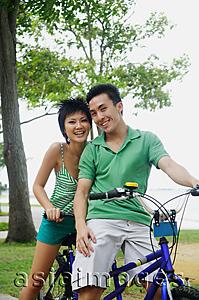 Asia Images Group - Couple on tandem bicycle, looking at camera