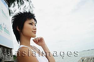Asia Images Group - Woman in sleeveless top, standing by sea, looking away