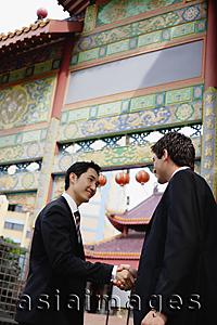Asia Images Group - Businessmen shaking hands, temple gate in the background