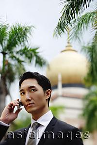 Asia Images Group - Businessman using mobile phone, mosque in the background