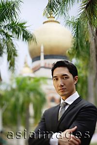 Asia Images Group - Businessman standing with arms crossed, mosque in the background