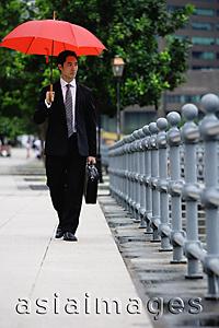 Asia Images Group - Businessman walking under red umbrella