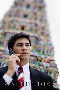 Asia Images Group - Businessman using mobile phone, Hindu temple in the background