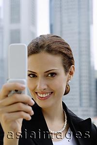 Asia Images Group - Businesswoman using mobile phone, photo messaging, looking at camera