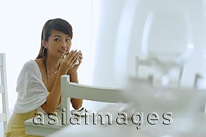 Asia Images Group - Woman sitting at cafe table, holding cup to lips, looking away