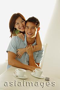 Asia Images Group - Woman embracing man from behind, both smiling at camera