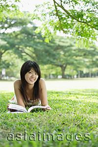 Asia Images Group - Young woman lying on grass, smiling at camera