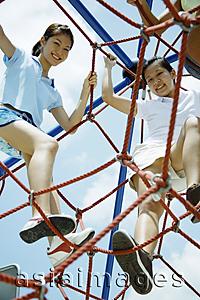 Asia Images Group - Young women climbing ropes at playground, smiling at camera
