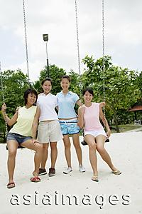 Asia Images Group - Young women sitting on swings, smiling at camera
