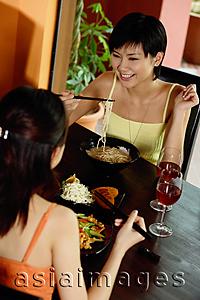 Asia Images Group - Two young women having a meal in restaurant