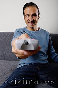 Asia Images Group - Man holding TV remote control, pointing towards camera