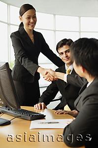 Asia Images Group - Businesswoman shaking hands on seated businessman in office