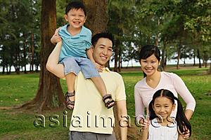 Asia Images Group - Family of four, standing in park, smiling at camera