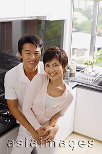 Asia Images Group - Couple embracing in kitchen, smiling at camera