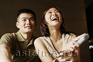 Asia Images Group - Couple watching TV, woman holding remote control