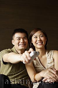 Asia Images Group - Couple watching TV, man holding remote control