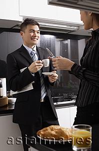 Asia Images Group - Executives in kitchen, man having coffee, woman holding mobile phone