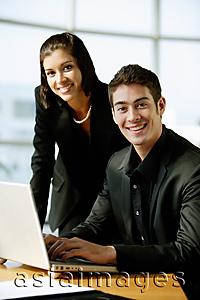 Asia Images Group - Executives dressed in black, sitting next to laptop, looking at camera, smiling