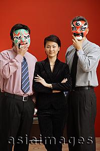 Asia Images Group - Businesswoman standing between two businessmen with Chinese masks over their faces