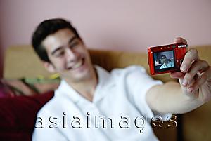 Asia Images Group - Man holding camera, taking photograph of himself