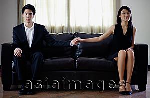 Asia Images Group - Man and woman sitting on sofa, holding hands