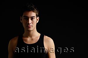 Asia Images Group - Man in black sleeveless top, standing against black background
