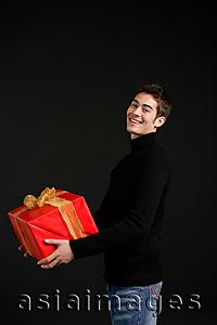 Asia Images Group - Man in black turtleneck carrying big red box with gold ribbon