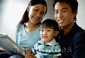 Asia Images Group - Family smiling at camera, father holding a book
