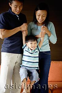 Asia Images Group - Mother and father holding arms of young boy