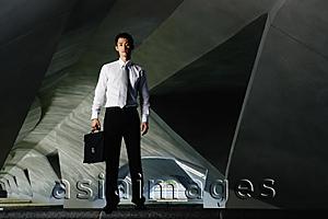 Asia Images Group - Executive holding briefcase, looking at camera
