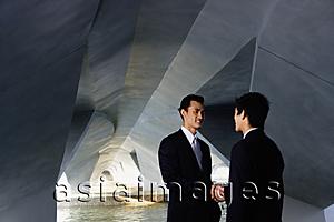 Asia Images Group - Two businessmen standing in tunnel structure, shaking hands