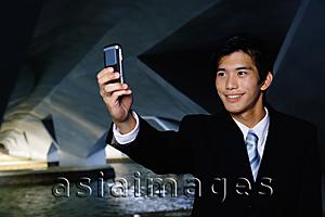 Asia Images Group - Businessman in tunnel, taking a picture of himself with camera phone