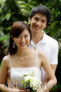 Asia Images Group - Couple standing in garden, smiling at camera