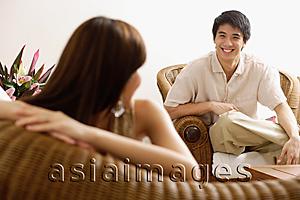 Asia Images Group - Couple at home in living room, woman turning to look at man